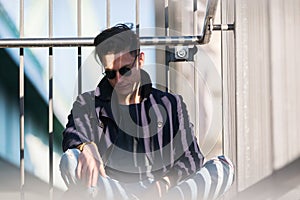 Young man sits beside a handrail