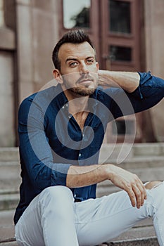 Young man sits and ponders on stairs near building