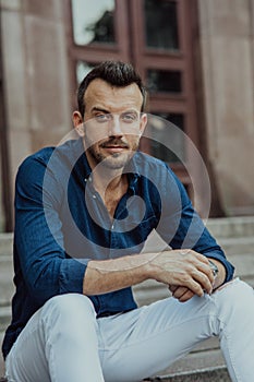 Young man sits and ponders on stairs near building