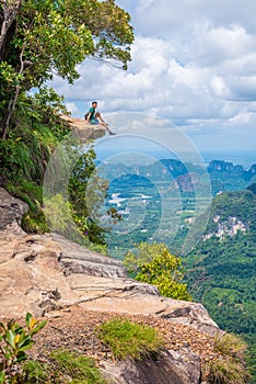 Young man sits on rock at Dragon Crest or Khuan Sai at Khao Ngon Nak Nature Trail in Krabi, Thailand