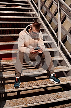A young man sits on the steps in the city. Urban style. Lifestyle photo