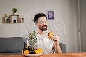 A young man sits at a table and talks about the usefulness of fruits, he picks them up and shows orange