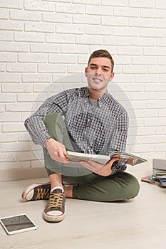 Young man sits with textbooks on the floor