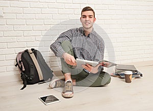 Young man sits with textbooks on the floor