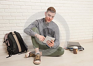 Young man sits with textbooks on the floor