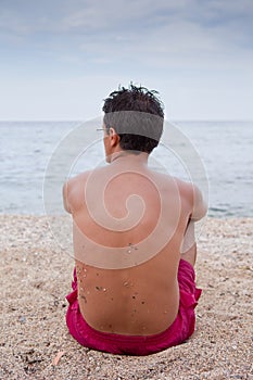 Young man sitting alone on the beach