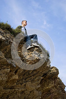 A young man sitting alone on the cliff