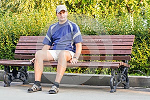 A young man is sitting alone on a park bench