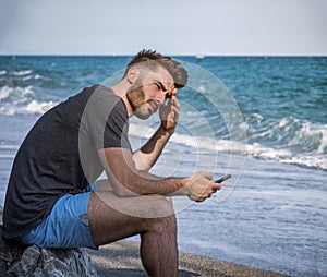 Young man sitting on a beach alone and lonely