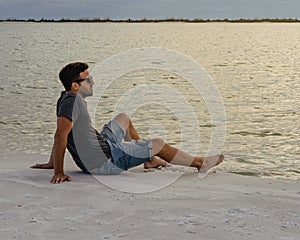 Young man sitting on the beach looking at the sea and relaxing. Lifesyle concept