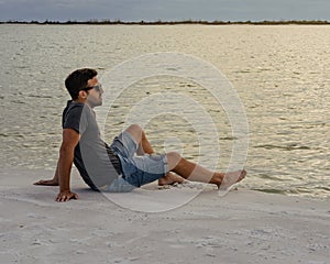 Young man sitting on the beach looking at the sea and relaxing. Lifesyle concept photo