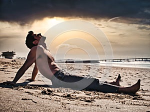 Young man sitting on beach at sunset