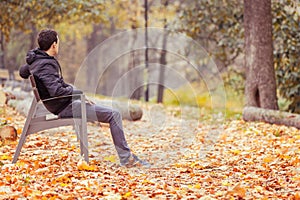 Young man sitting on a bench in a park