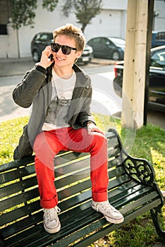 Young man sitting on a bench talking on the phone