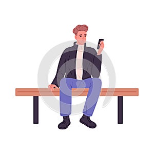 Young man sitting on bench, using mobile phone. Person with smartphone in hands. Guy with cellphone texting, looking at