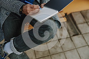 Young man sitting on bench and writing in notebook