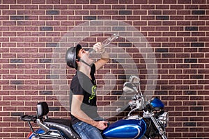 Young man sitting on a bike drinking alcohol