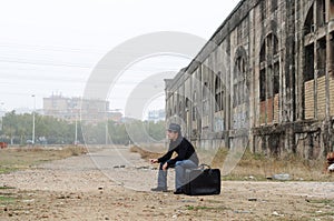 Young man sitting on black suitcase photo