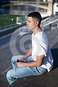 Young man sitting on bleachers watching football