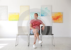 Young man sitting on chair at exhibition