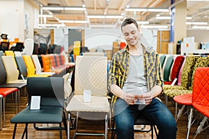 Young man sitting on chair in furniture store