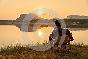 A young man sitting on a chair at mountain lake with relaxing mood, lonely man, Asian man travel alone