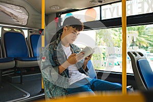 Young man sitting in city bus and reading a book.