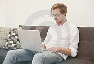 Young man sitting on couch with laptop