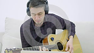 Young man sitting on a couch and playing guitar