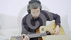 Young man sitting on a couch and playing guitar