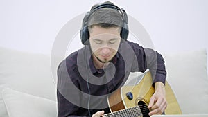 Young man sitting on a couch and playing guitar