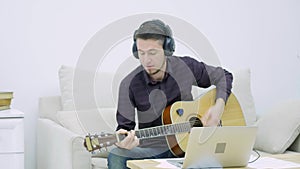 Young man sitting on a couch and playing guitar