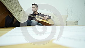 Young man sitting on a couch and playing guitar