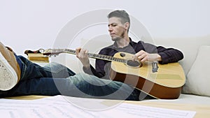 Young man sitting on a couch and playing guitar