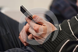 A young man, sitting on the couch to rest with a smartphone in ha