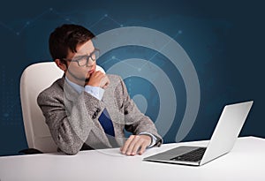 Young man sitting at desk and typing on laptop