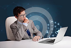 Young man sitting at desk and typing on laptop with social netwo