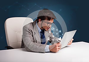 Young man sitting at desk and typing on laptop with social network icons
