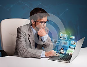 Young man sitting at desk and watching his photo gallery on laptop