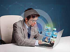 Young man sitting at desk and watching his photo gallery on laptop