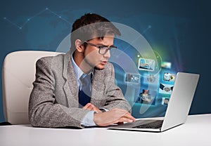 Young man sitting at desk and watching his photo gallery on laptop