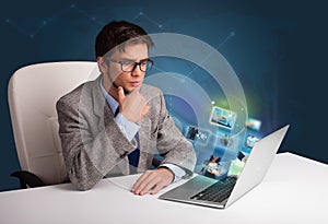 Young man sitting at desk and watching his photo gallery on laptop