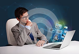 Young man sitting at desk and watching his photo gallery on laptop