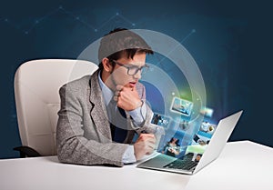 Young man sitting at desk and watching his photo gallery on laptop