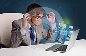 Young man sitting at desk and watching his photo gallery on laptop