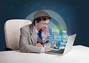 Young man sitting at desk and watching his photo gallery on laptop