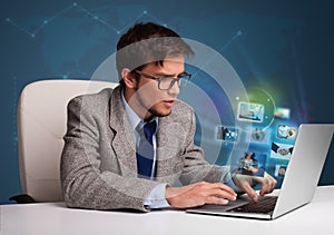 Young man sitting at desk and watching his photo gallery on laptop