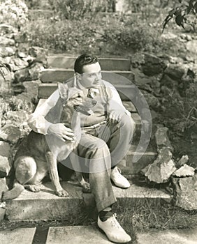 Young man sitting with dog on steps outdoors