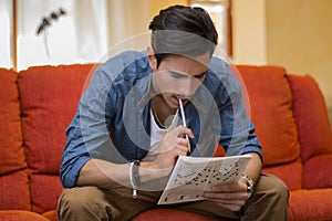 Young man sitting doing a crossword puzzle