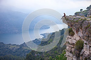 Young man sitting on edge of cliff